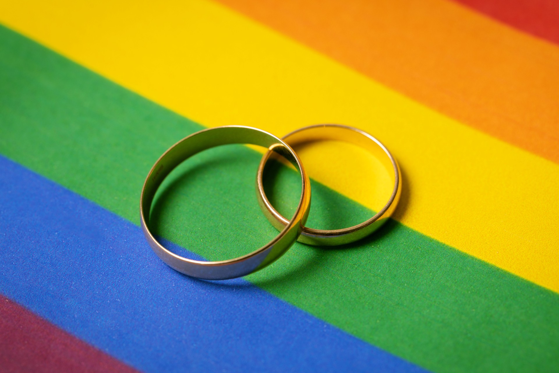 same-sex marriage concept - two wedding rings on lgbt rainbow flag